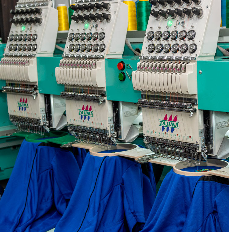 Multi-head embroidery machines stitching blue shirts